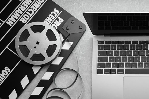 Flat lay composition with camera, film reel and laptop on grey textured table