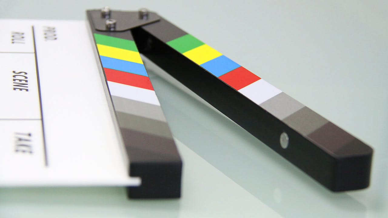 about-02 Colorful clapper board on a white surface, used in filmmaking. Ideal for entertainment and movie themes.